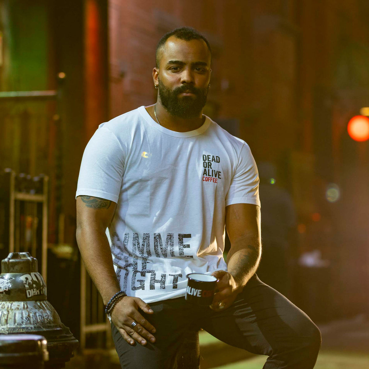 Model im weißen DEAD OR ALIVE COFFEE T-Shirt mit schwarzer Kaffeetasse