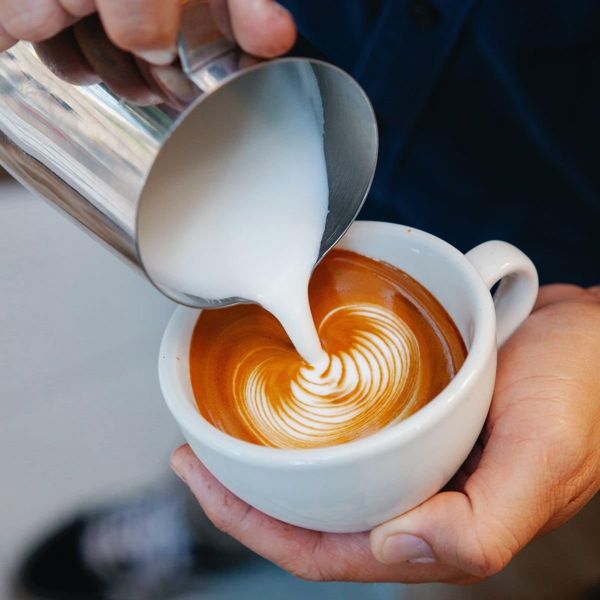 Milch wird für Latte Art in eine Tasse Espresso gegossen