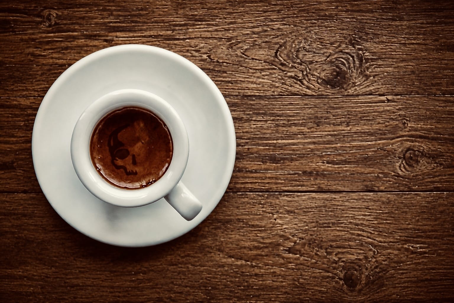Espressotasse mit Totenkopf-Crema auf dunklem Holztisch